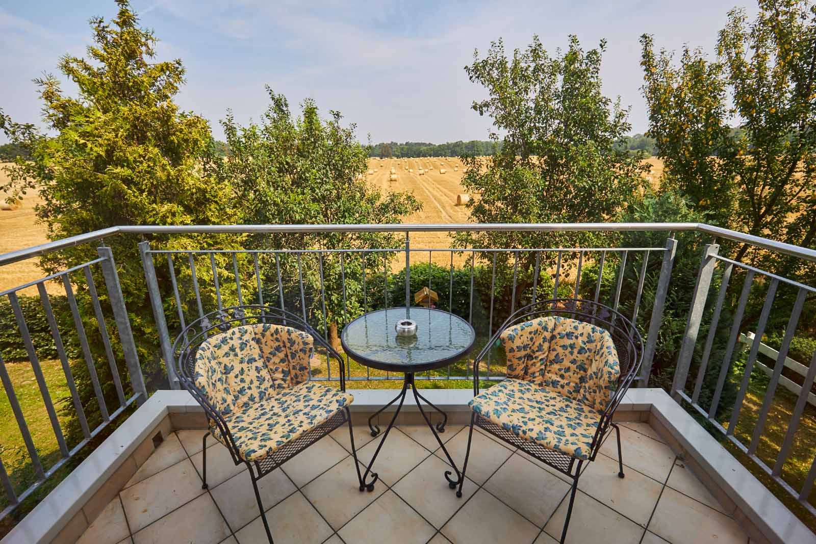 Privater Balkon mit Sitzmöbeln und Blick auf Felder und Natur, ideal zum Entspannen