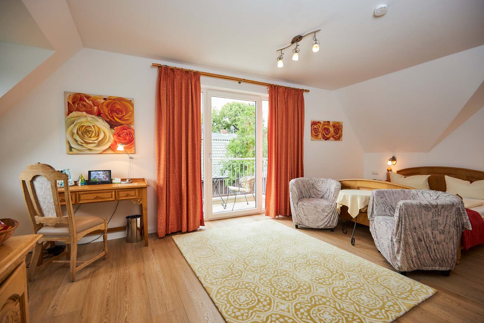 Großes Hotelzimmer mit Doppelbett, gemütlichen Sesseln, Schreibtisch und Balkonzugang, hell und modern