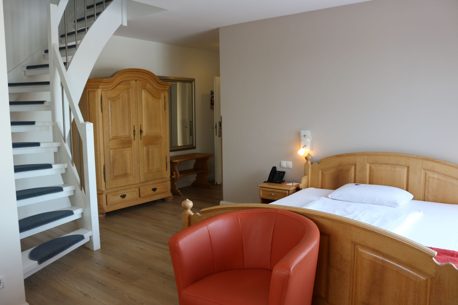 Großzügiges Deluxe Hotelzimmer mit Holzmöbeln, Doppelbett, Sitzbereich und Treppe zur zweiten Ebene