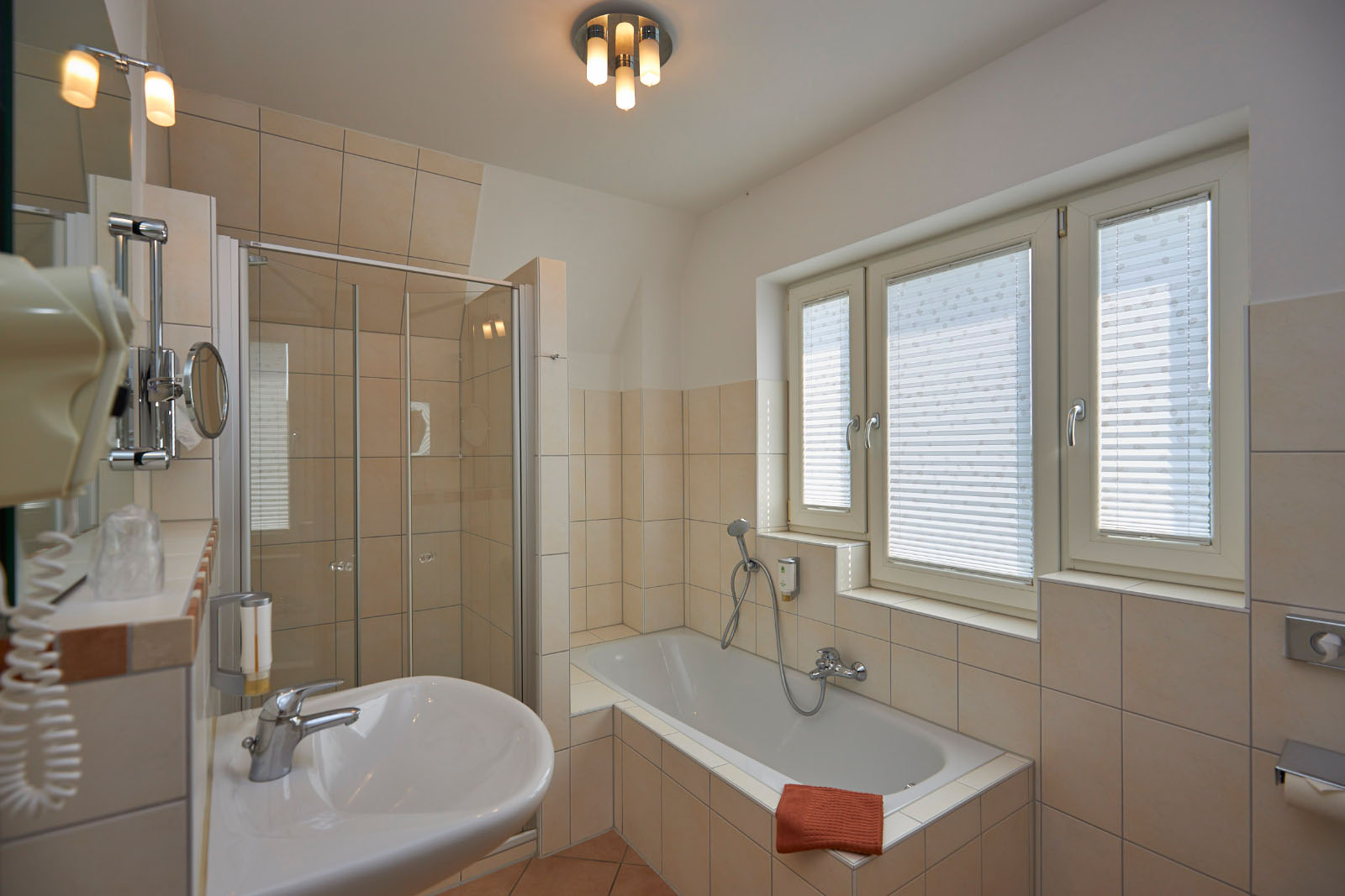 Großes Badezimmer mit Badewanne, separater Dusche, Waschbecken und Tageslichtfenster