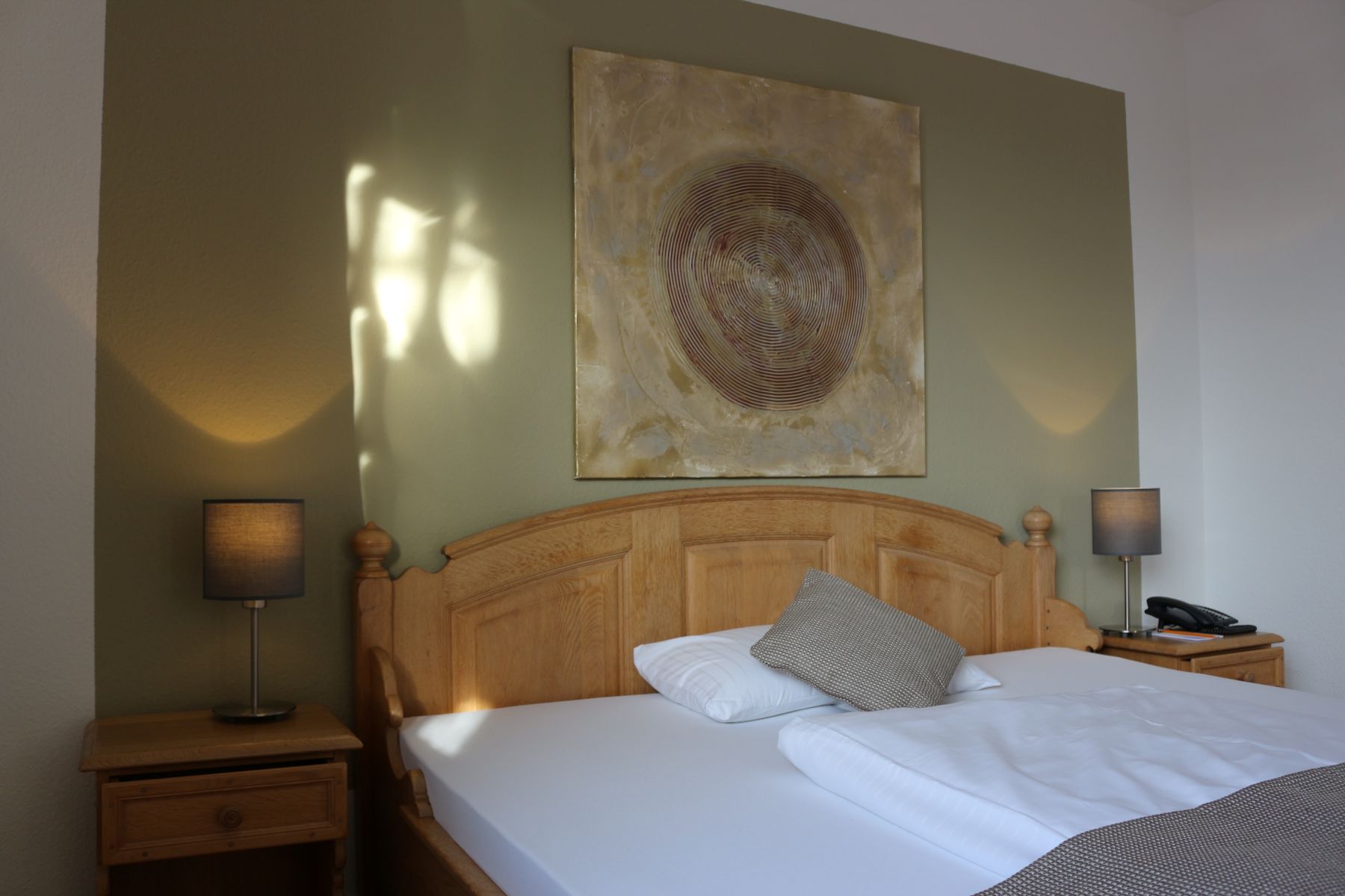 Comfortable double room with wooden bed, bedside tables, lamps and decorative mural