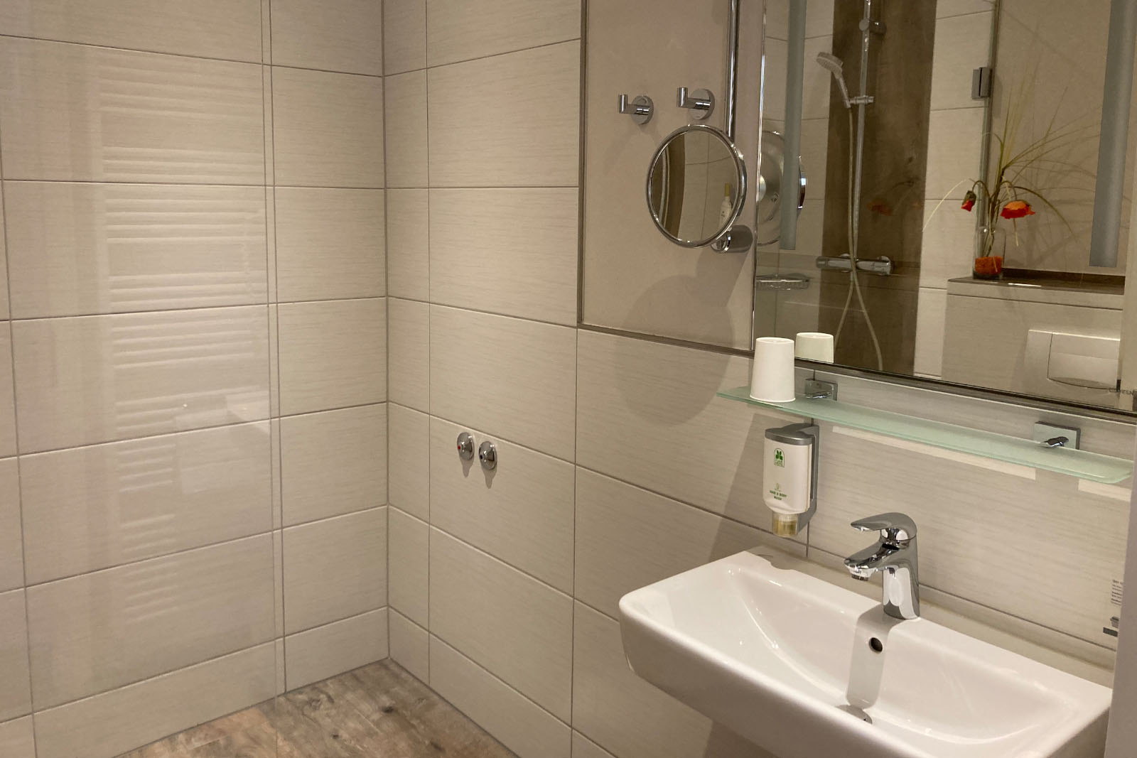 Elegant bathroom with washbasin, wall mirror, vanity mirror and modern tiles