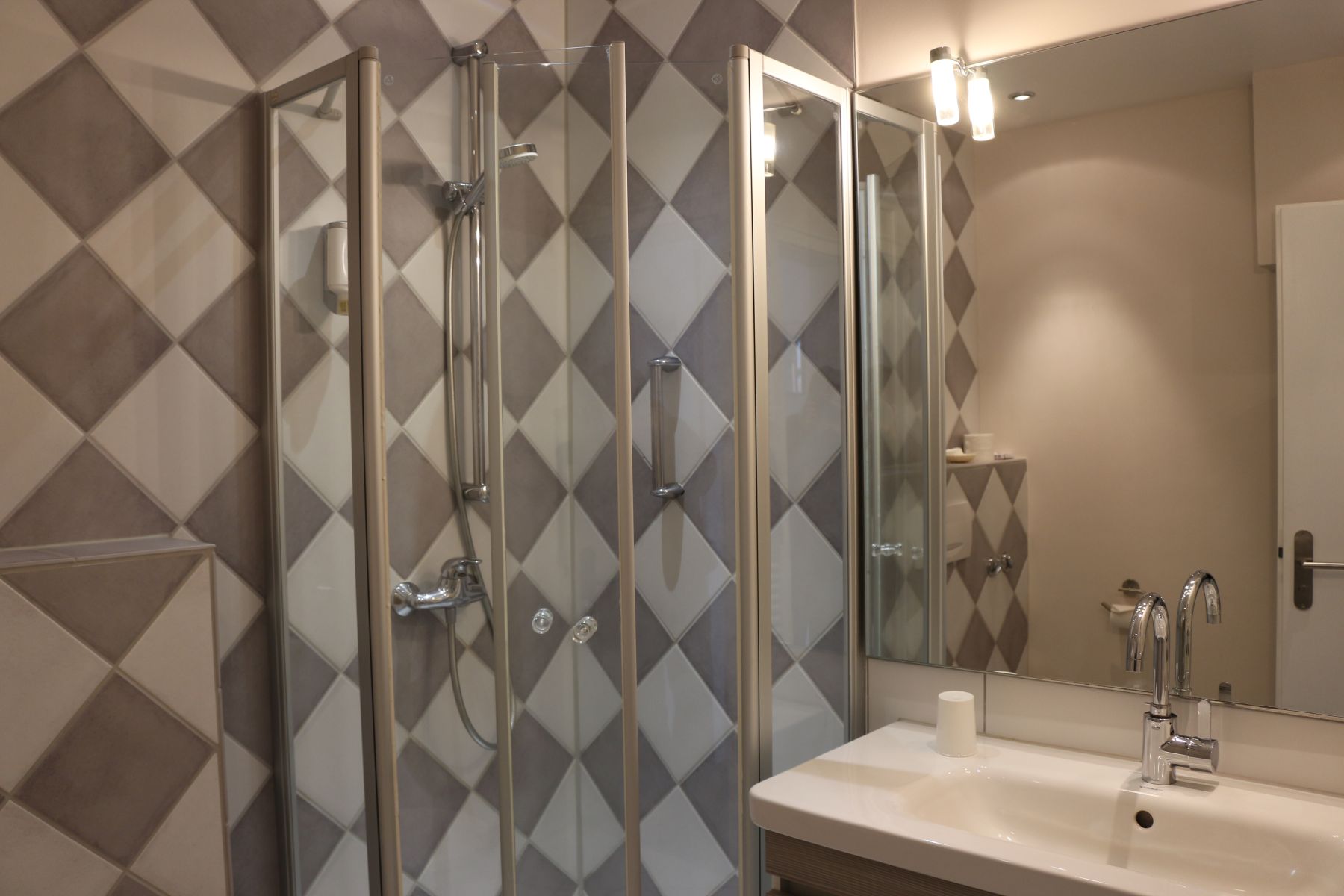 Bathroom with shower cubicle, patterned tiles and washbasin with large mirror