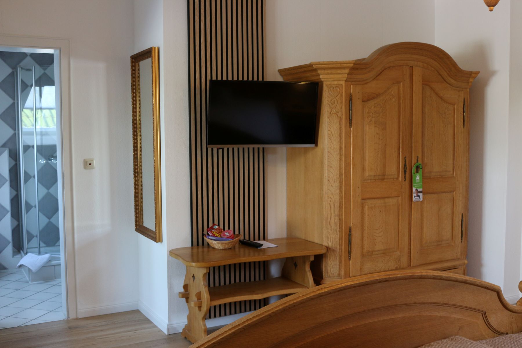 Hotelzimmer mit Flachbildfernseher, Holzmöbeln und Zugang zum Badezimmer, klassisch und komfortabel eingerichtet