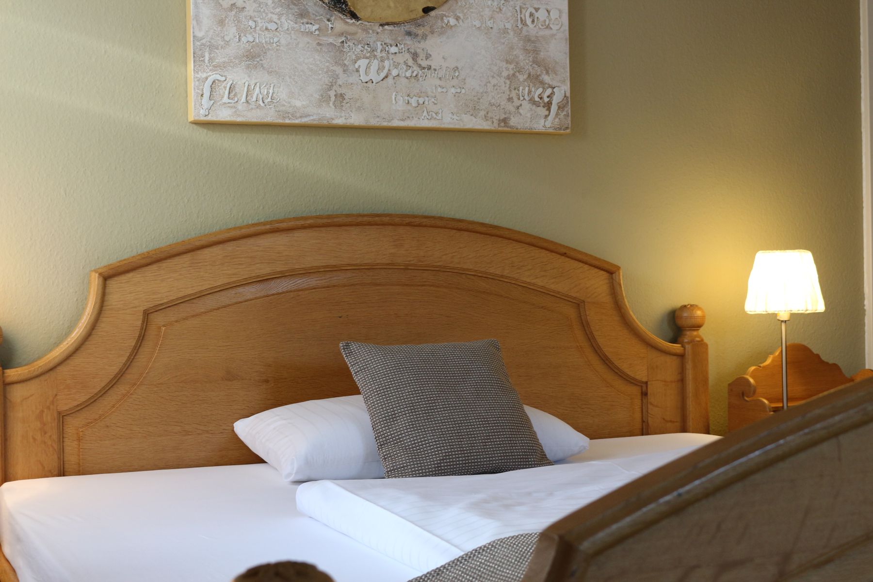 Komfortables Doppelbett mit hochwertiger Bettwäsche und Holzkopfteil in stilvoll eingerichtetem Hotelzimmer