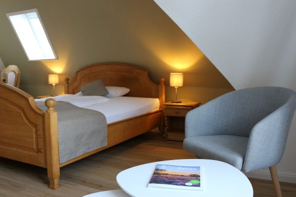 Gemütliches Hotelzimmer mit Doppelbett, Dachfenster, Sessel und warmem Lichtambiente